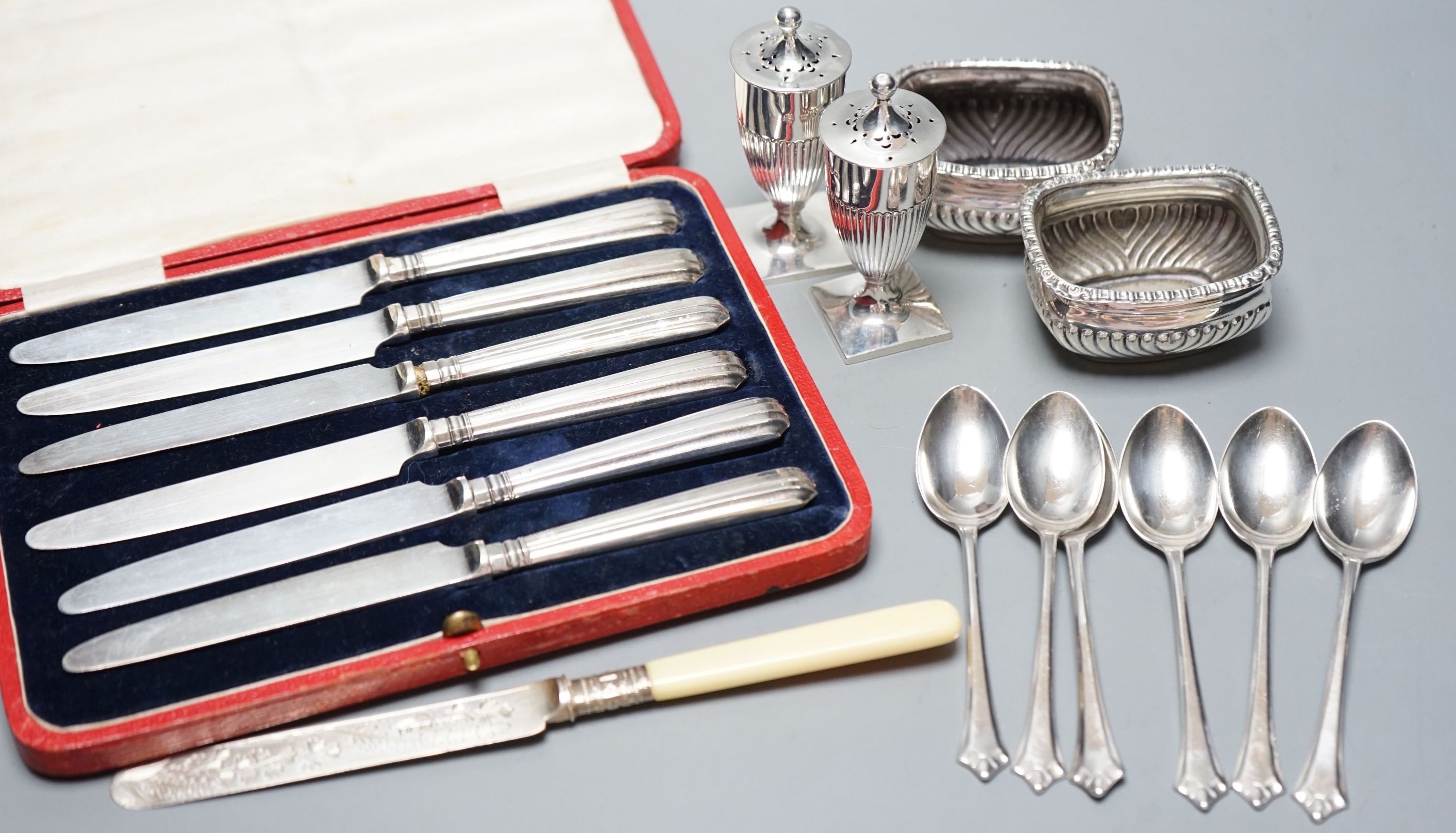 A pair of Victorian silver pepperettes, a pair of later silver salts, six silver teaspoons, a silver dessert knife and a cased set of silver handled tea knives.
